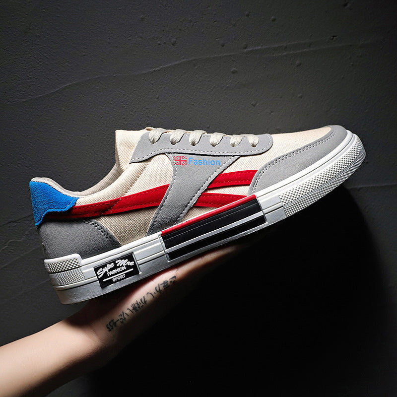 Trendy FashionRay sneaker with gray, red, and cream design, blue heel accent, on dark background.