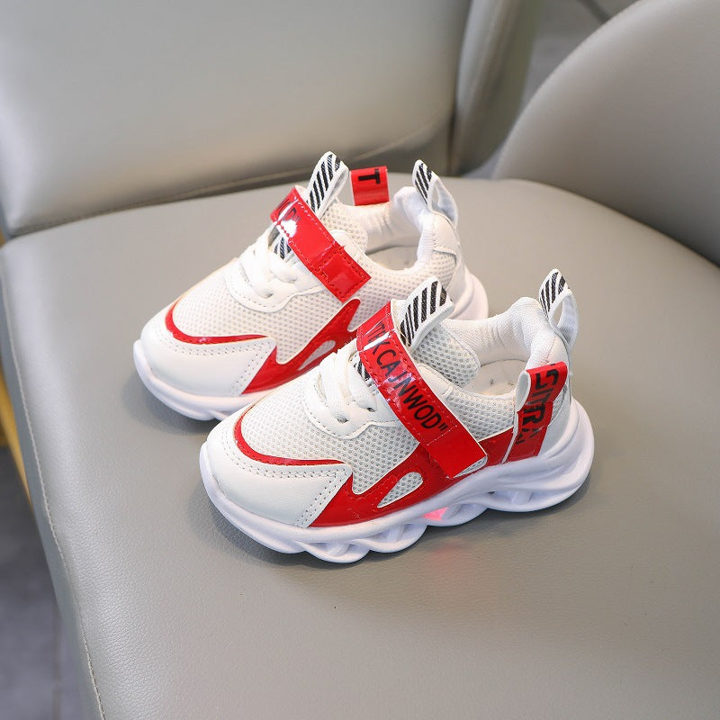 Trendy white and red kids' sneakers with mesh and bold accents on a gray chair, FashionRay style