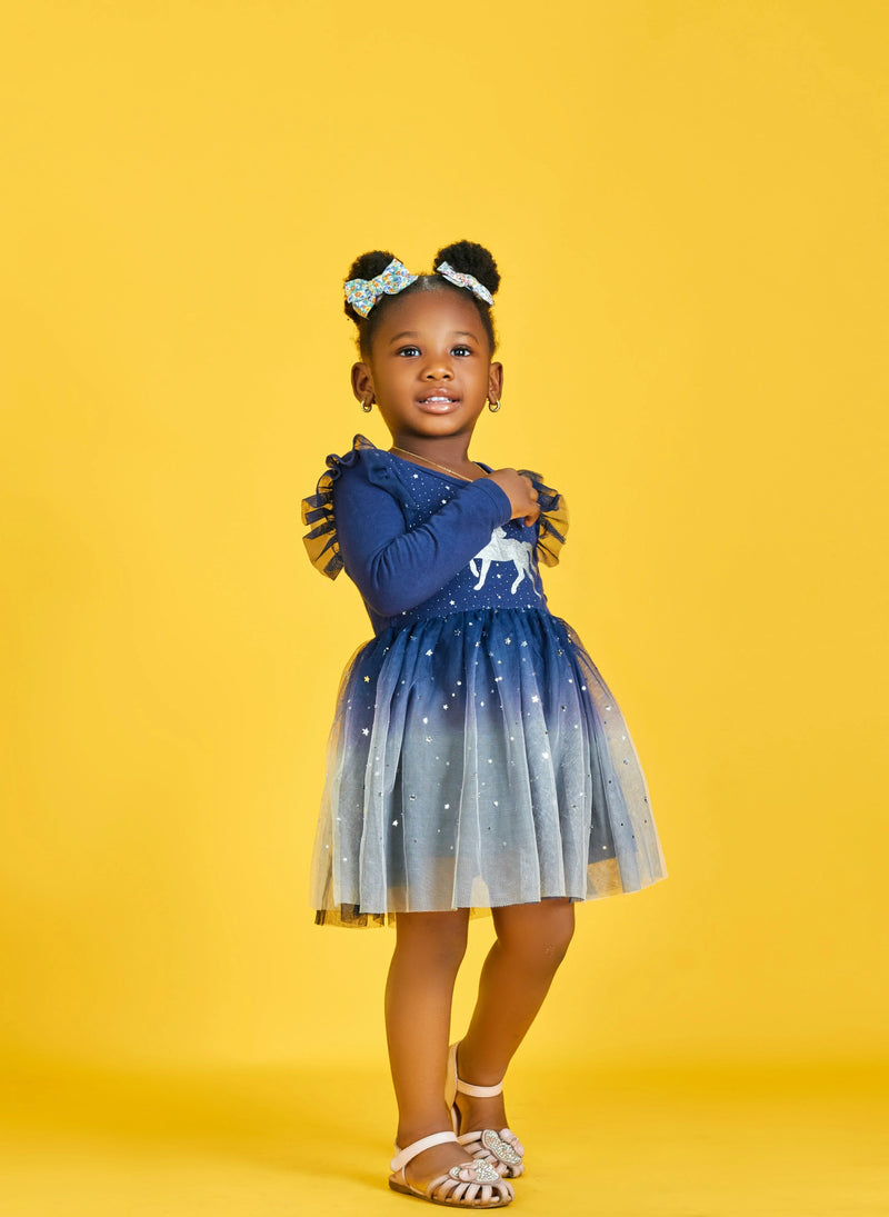 Little girl in a blue starry dress posing on yellow background, kids fashion at FashionRay