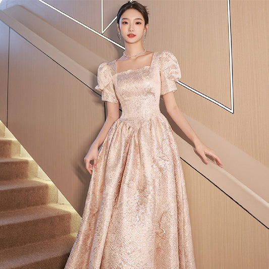 Elegant woman in a shimmering champagne gown with puff sleeves on staircase, FashionRay style