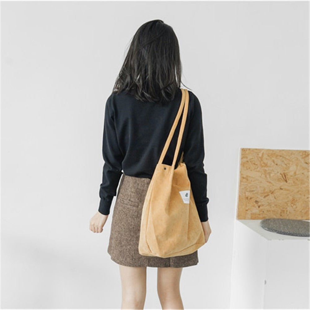 Woman in chic fall fashion outfit with brown mini skirt and black top, carrying yellow tote bag