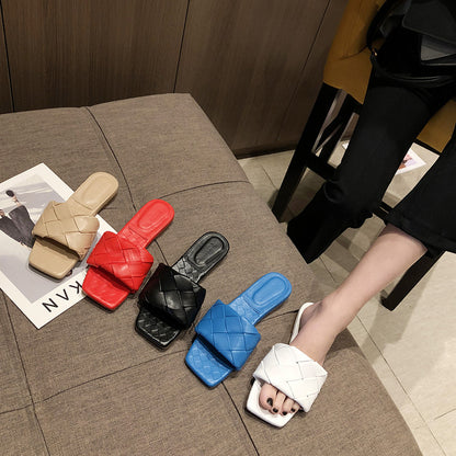 FashionRay woven slide sandals in beige, red, black, blue, and white on a sofa