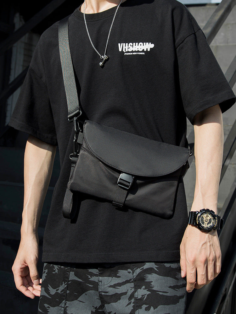 Man in black graphic t-shirt with crossbody bag, camouflage shorts, and watch, FashionRay style