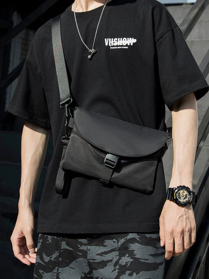 Man in black graphic t-shirt with crossbody bag, camouflage shorts, and watch, FashionRay style