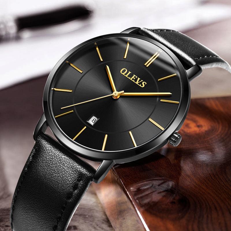 Sleek black OLEVS watch with gold accents and leather strap on polished wood surface
