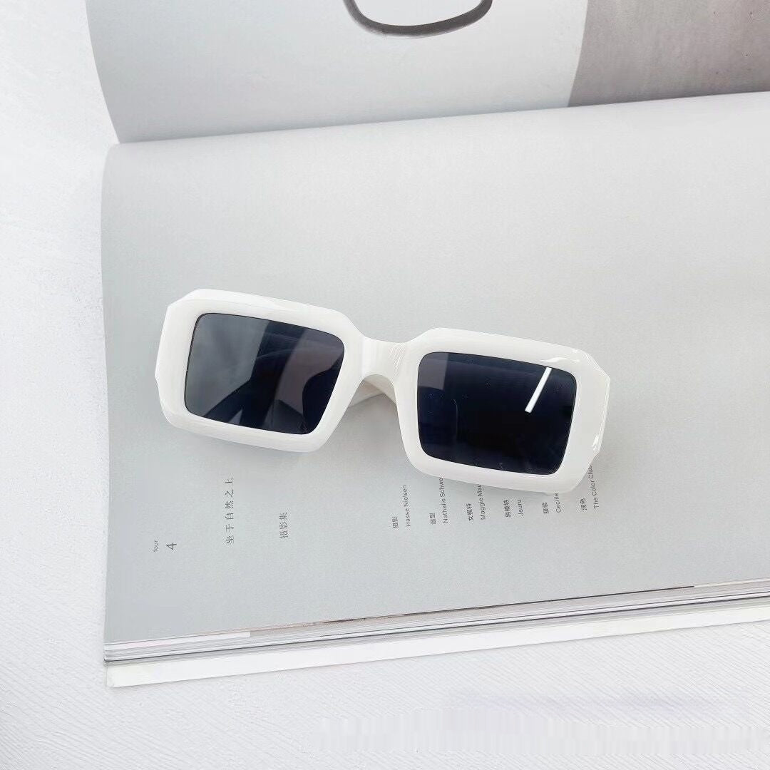 Trendy white square sunglasses with dark lenses on an open magazine, FashionRay style