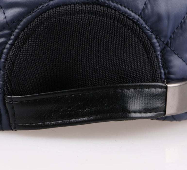 Closeup of navy quilted cap with black adjustable leather strap, FashionRay trendy accessory.