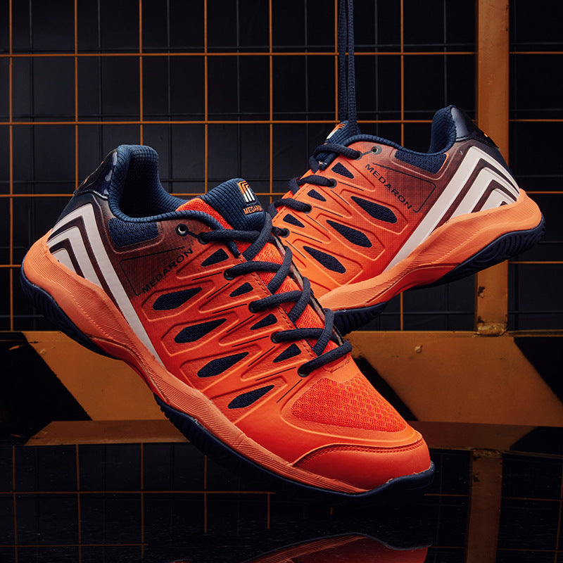 Bold orange athletic sneakers with navy accents, mesh details, and white graphic side stripes, displayed against a modern geometric backdrop on FashionRay.