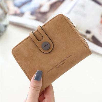 Woman holding a stylish tan wallet with button clasp, FashionRay trendy accessories.