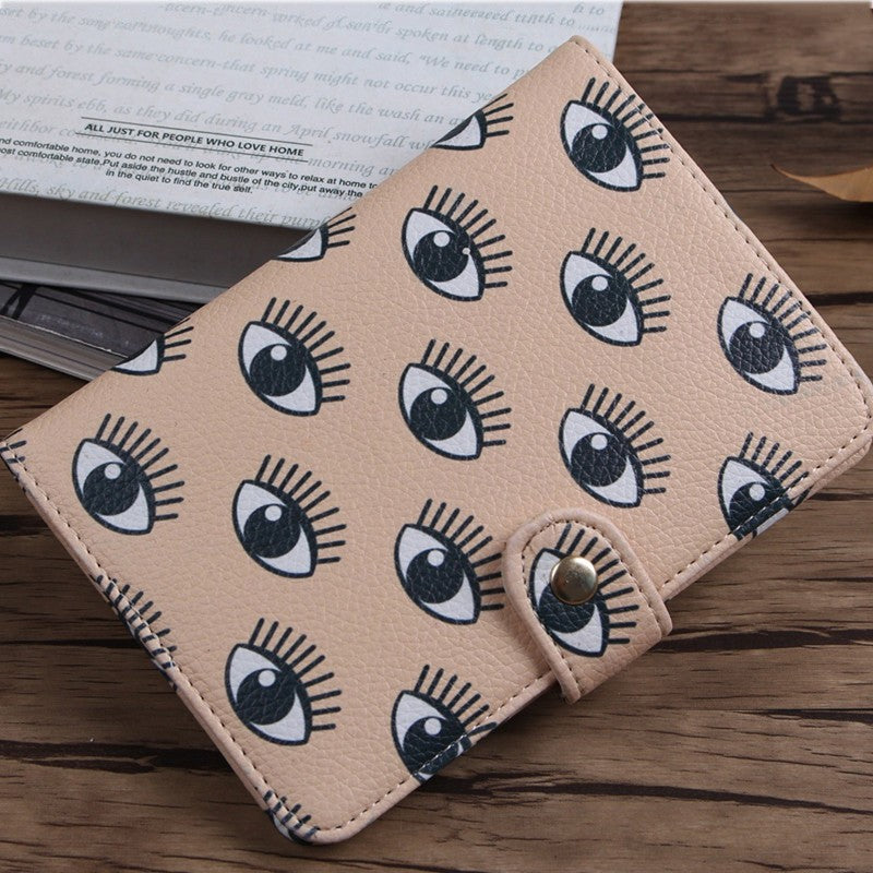 Beige faux leather wallet with trendy eye print, FashionRay accessory on wooden table
