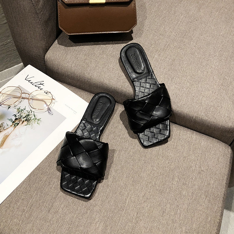 Black woven slides on beige sofa, next to brown purse and magazine, FashionRay style