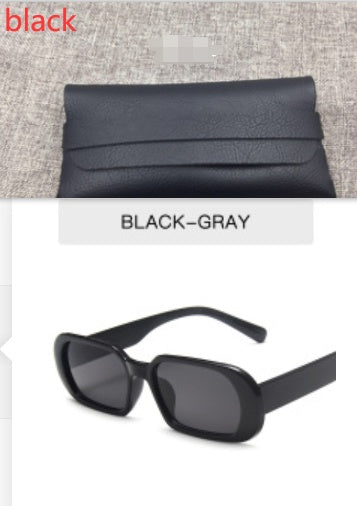 Black oval sunglasses with gray lenses and a textured black case on a neutral background, FashionRay
