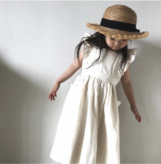 Girl in cream ruffle dress and straw hat, minimalist background, FashionRay style
