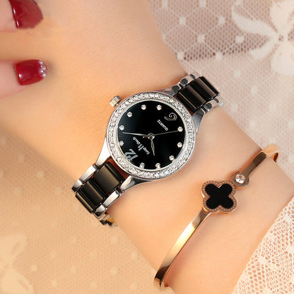 Elegant black and silver women's watch with crystal accents and a gold clover bracelet