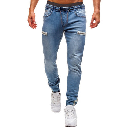 Men’s light blue denim joggers with zippered pockets, styled casually for FashionRay.