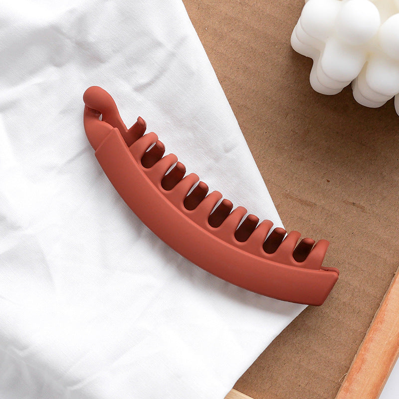 Matte brown hair banana clip on white fabric, trendy accessory at FashionRay