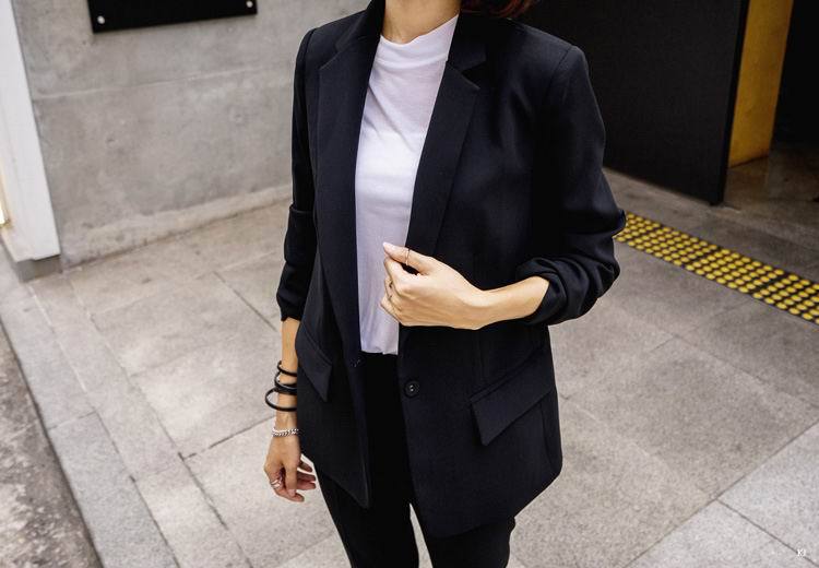 Woman in black blazer and white t-shirt standing on urban street, FashionRay style