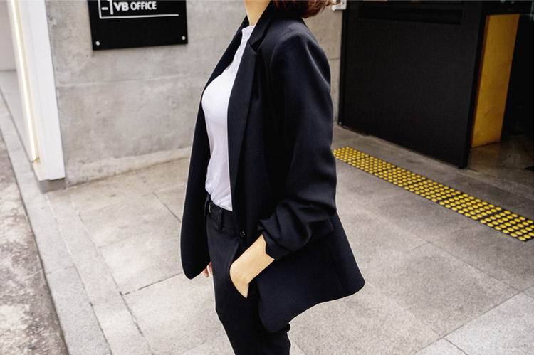 Woman in black blazer and white top standing outdoors, showcasing FashionRay trendy style