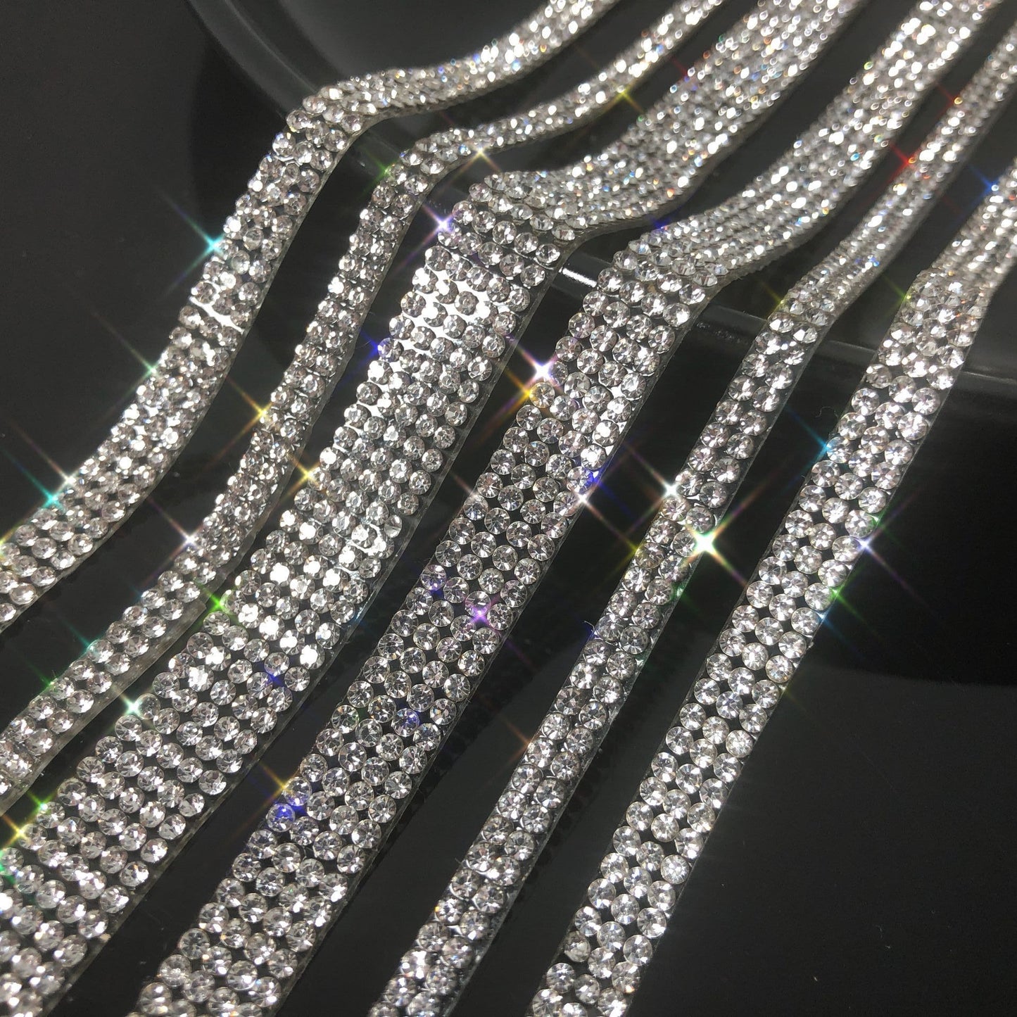 Rows of sparkling rhinestone belts on a black background, FashionRay trendy accessories