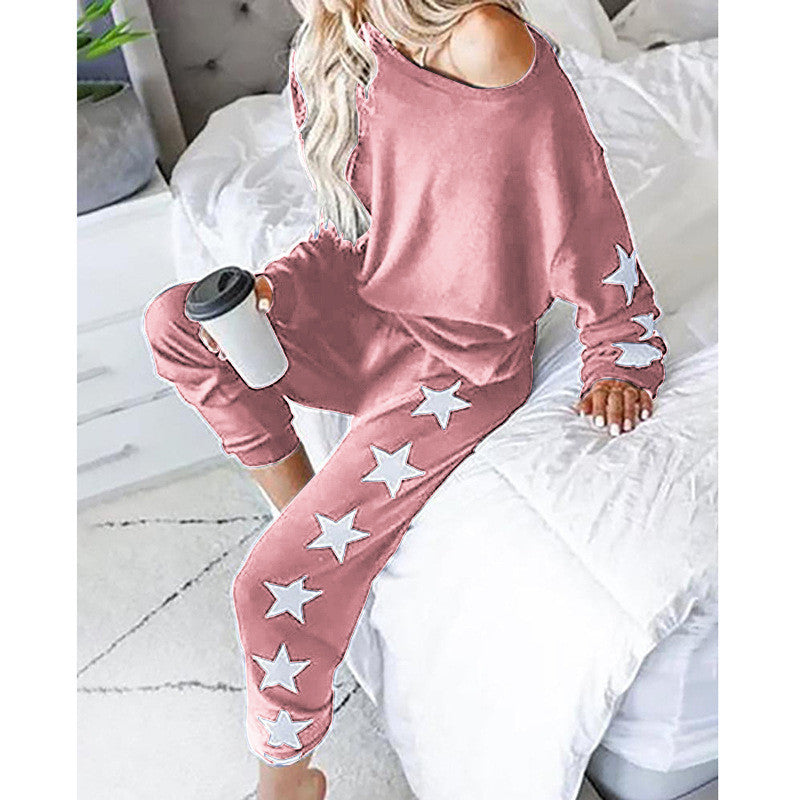 Woman in pink star-print loungewear from FashionRay sitting on a bed with coffee