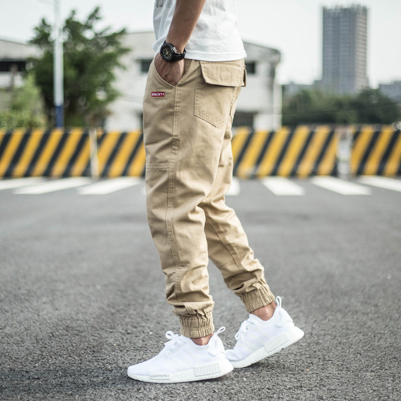 Man in khaki jogger pants and white sneakers modeling streetwear outdoors, FashionRay style