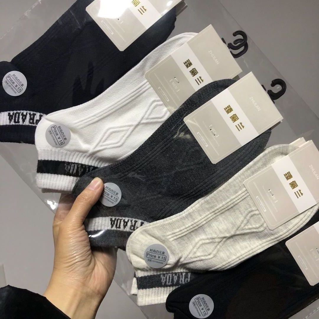 Hand holding assorted black, white, and gray FashionRay socks in retail packaging