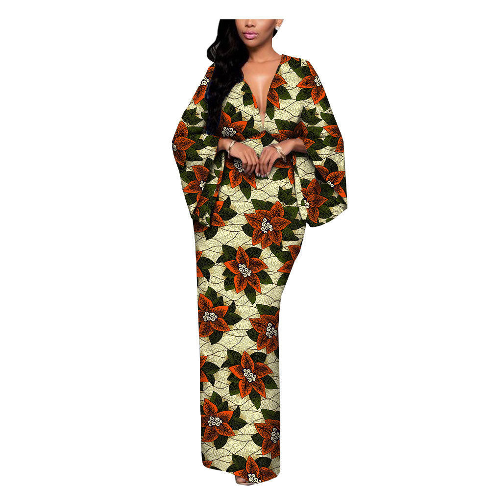 Woman in a long floral print dress with wide sleeves, bold orange and green pattern, FashionRay