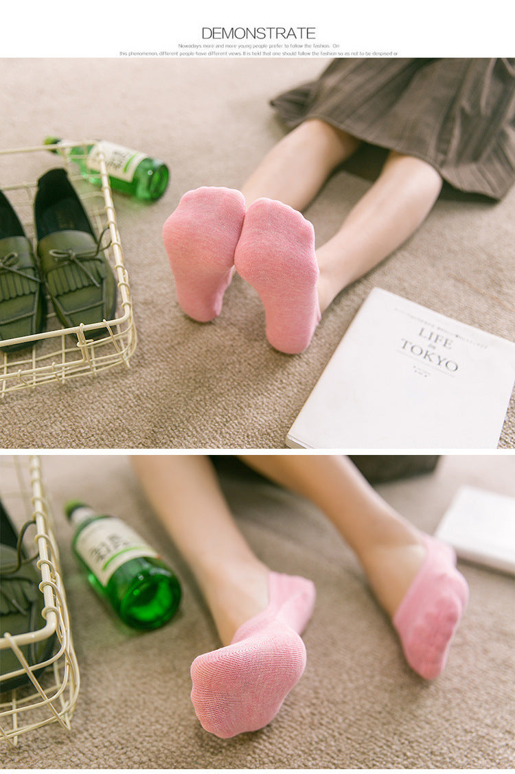 Woman wearing pink ankle socks relaxing on carpet with loafers, book, and green bottle nearby.