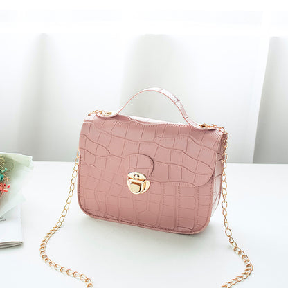 Blush pink crocodile pattern handbag with gold chain strap on white table, FashionRay style