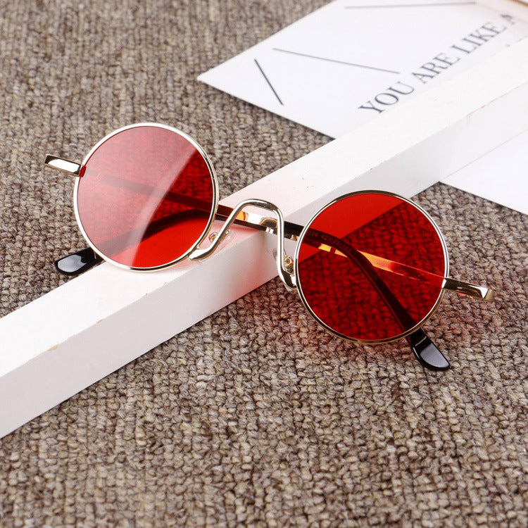 Trendy round sunglasses with red lenses and gold frames on a textured surface, FashionRay style