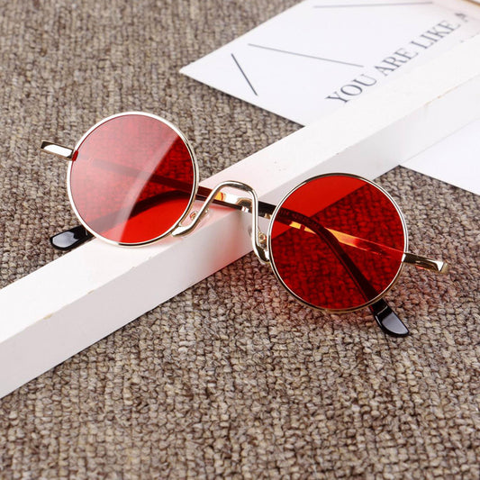 Trendy round sunglasses with red lenses and gold frames on a textured surface, FashionRay style