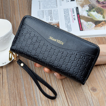 FashionRay black embossed leather wristlet wallet with gold zipper on a wooden table