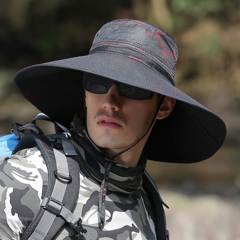 Man wearing wide-brim sun hat, sunglasses, and camo shirt outdoors, FashionRay style