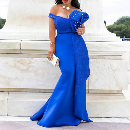 Woman in royal blue off-shoulder formal gown with pearl accents, standing outdoors
