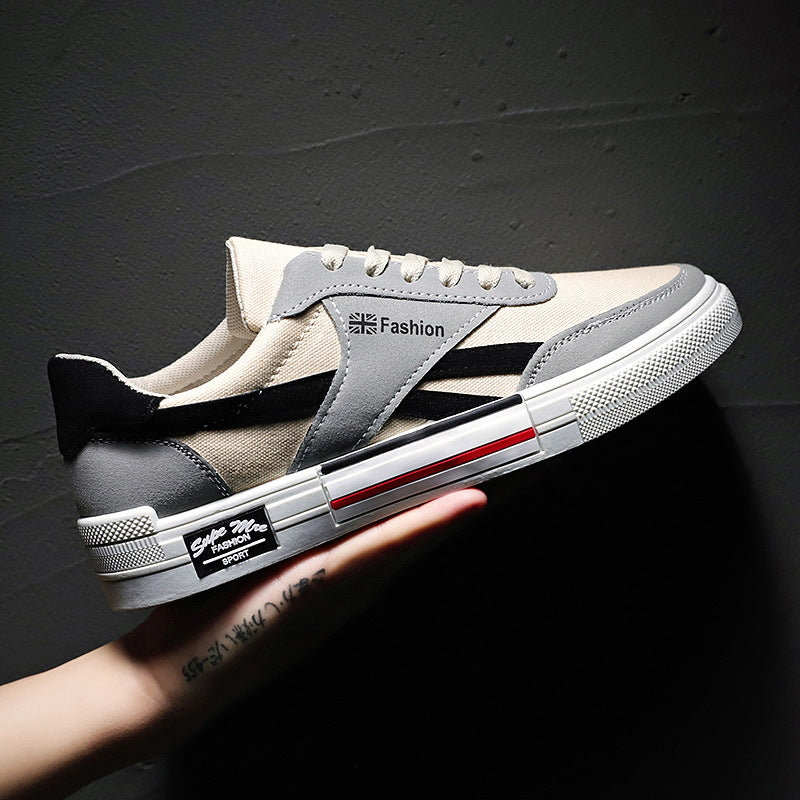 Trendy beige and gray FashionRay sneaker with black accents held against a dark wall