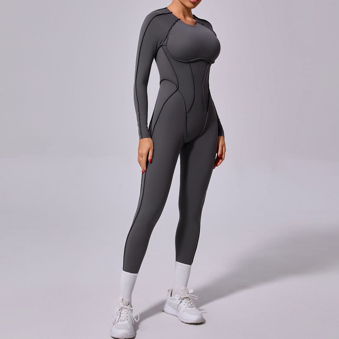 Woman wearing a sleek gray long-sleeve jumpsuit with white sneakers, FashionRay activewear