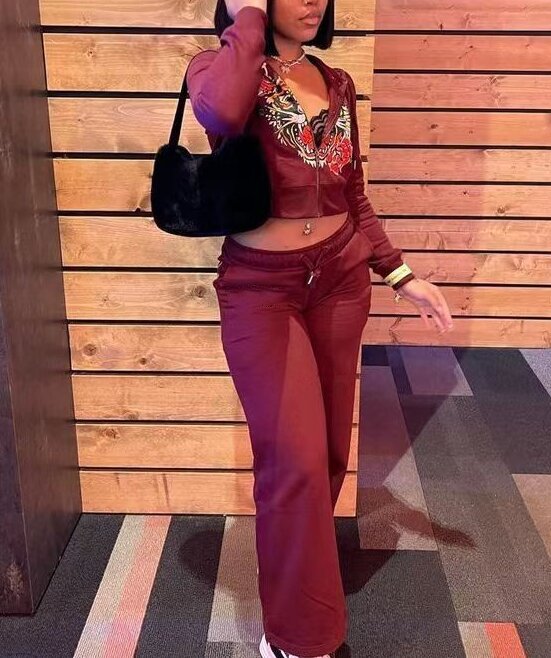 Woman in a maroon two-piece tracksuit with embroidered floral detail, black handbag, trendy streetwear style