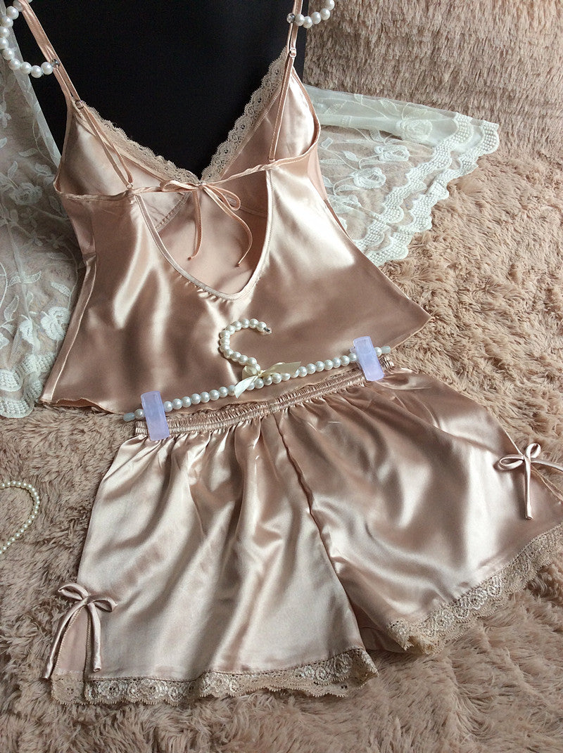 Silky beige camisole and shorts sleepwear set with lace trim, displayed on plush fabric
