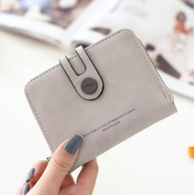 Gray faux leather wallet with button clasp, held by hand, trendy accessory from FashionRay