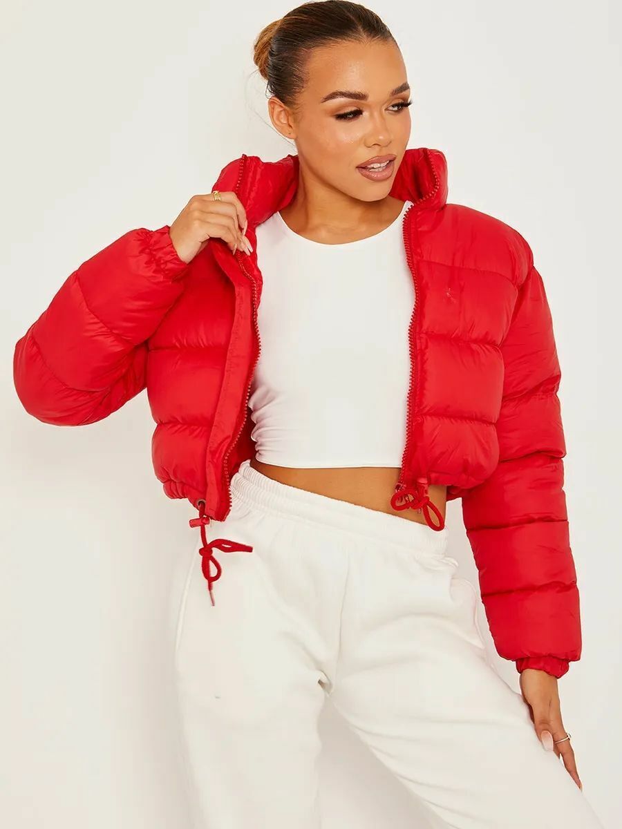 Woman wearing a trendy red puffer jacket, white crop top, and white sweatpants, FashionRay