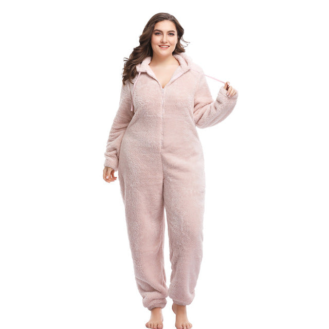 Plus size woman in a soft pink hooded fleece onesie from FashionRay, standing on white background