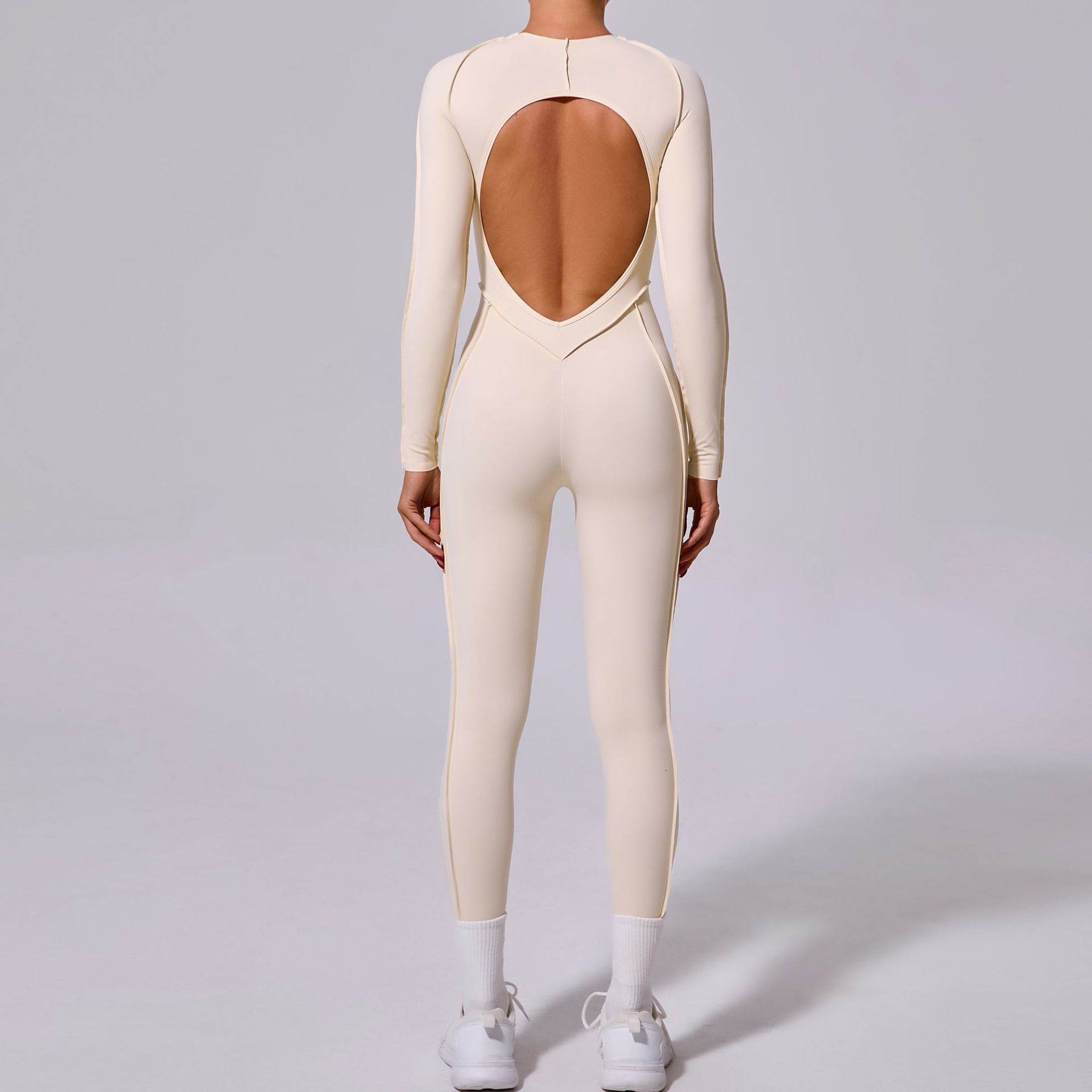 Woman in cream open-back jumpsuit and white sneakers, FashionRay trendy style