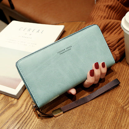 FashionRay aqua blue zip wallet held by hand on table with coffee and magazine