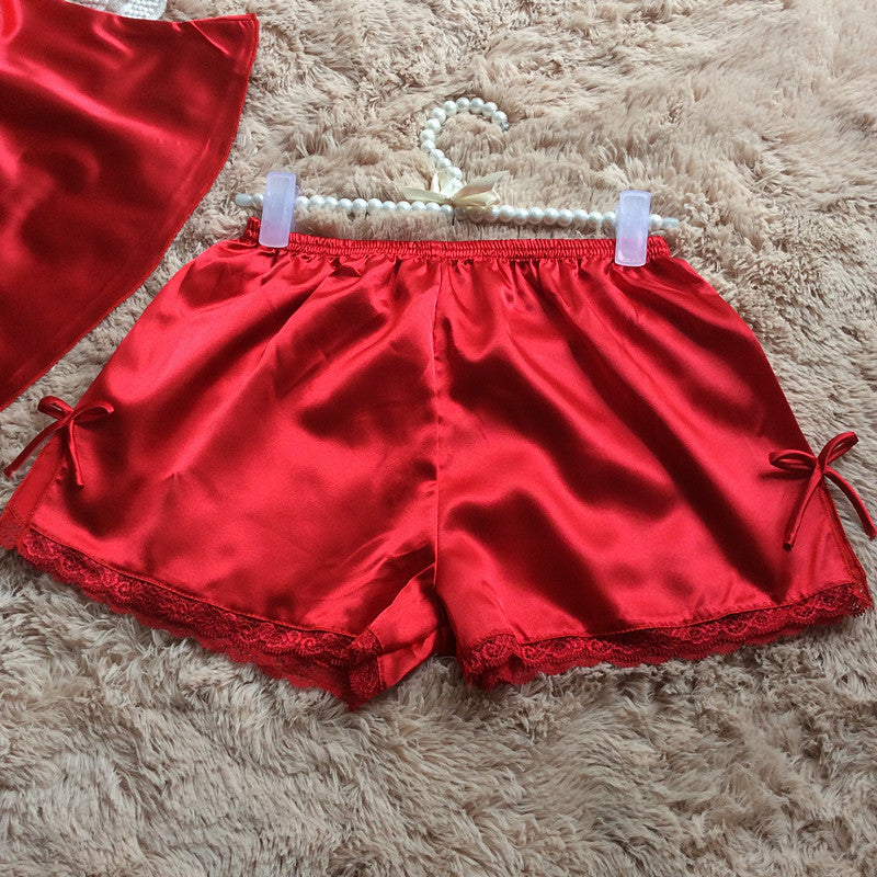 Red satin lace-trimmed shorts with ribbon detail on plush beige rug, FashionRay sleepwear.