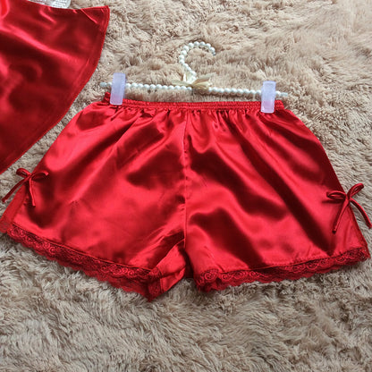 Red satin lace-trimmed shorts with ribbon detail on plush beige rug, FashionRay sleepwear.