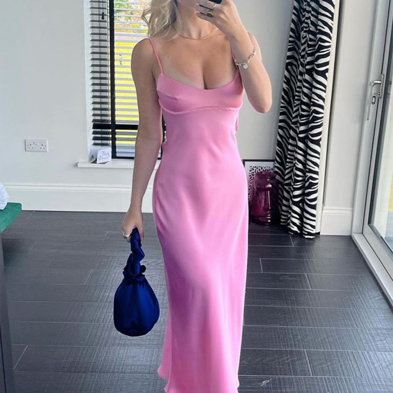Woman in a pink satin slip dress holding a blue bag, modern chic fashion at FashionRay