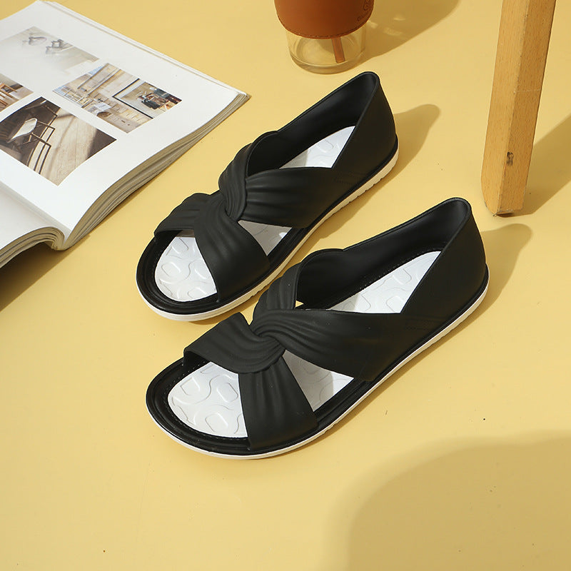 Black slip-on sandals with knotted design on white sole, displayed on yellow background