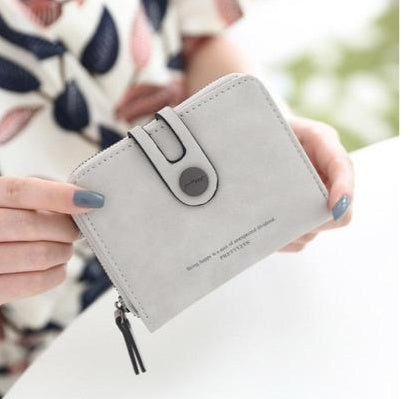 Woman holding a stylish light gray wallet from FashionRay, featuring a snap closure.