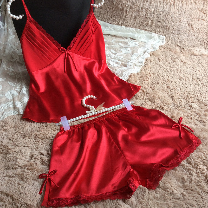 Red satin camisole and shorts sleepwear set with lace trim on plush bedding at FashionRay