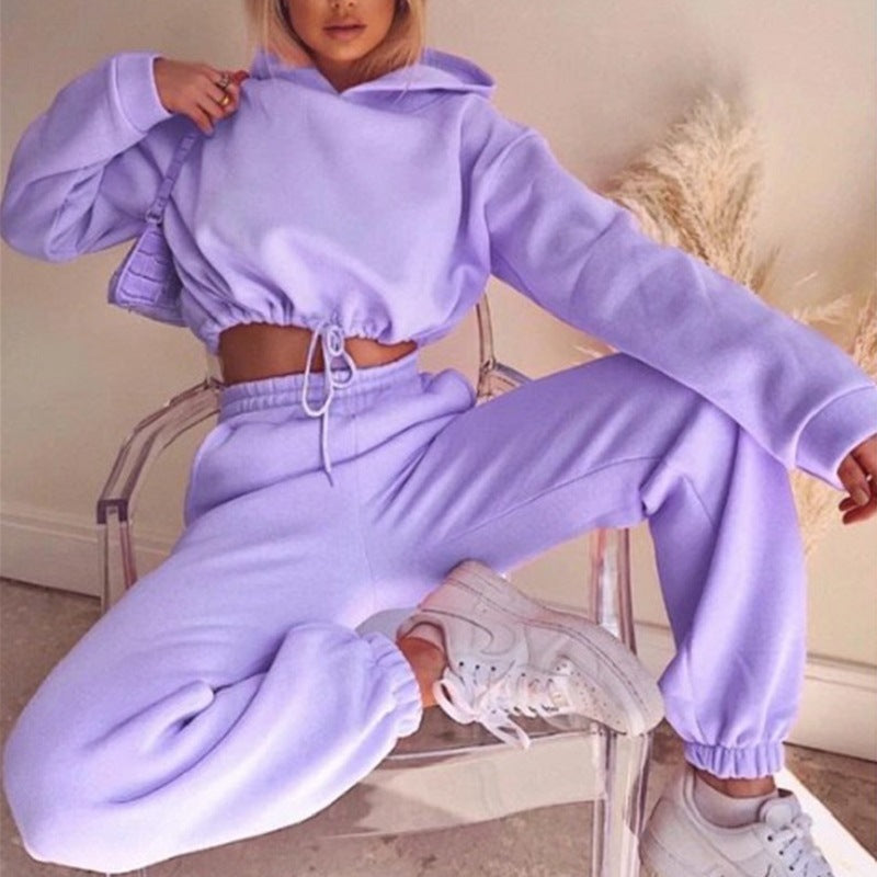 Woman in lilac cropped hoodie and joggers set with white sneakers, casual lounge fashion